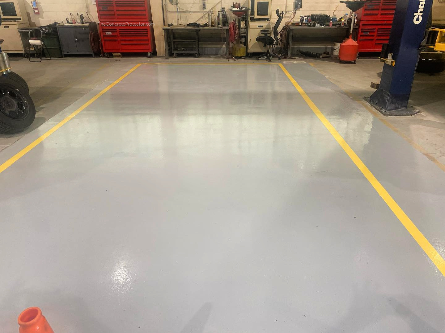 Glossy gray 123 Resinous warehouse floor with yellow safety lines and a work vehicle