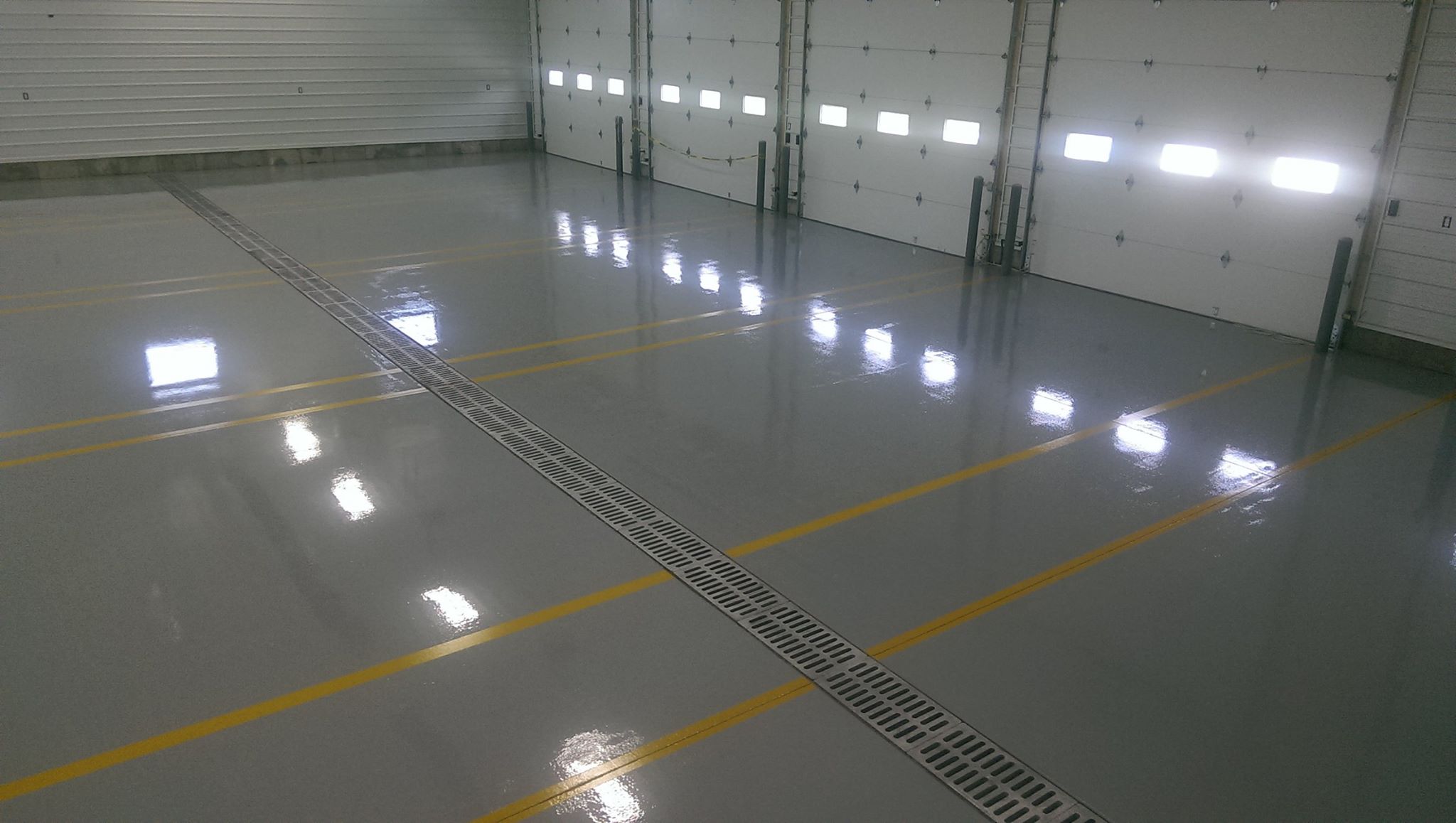 Gray 123 Resinous warehouse bay floor with yellow striping and a roll-up door