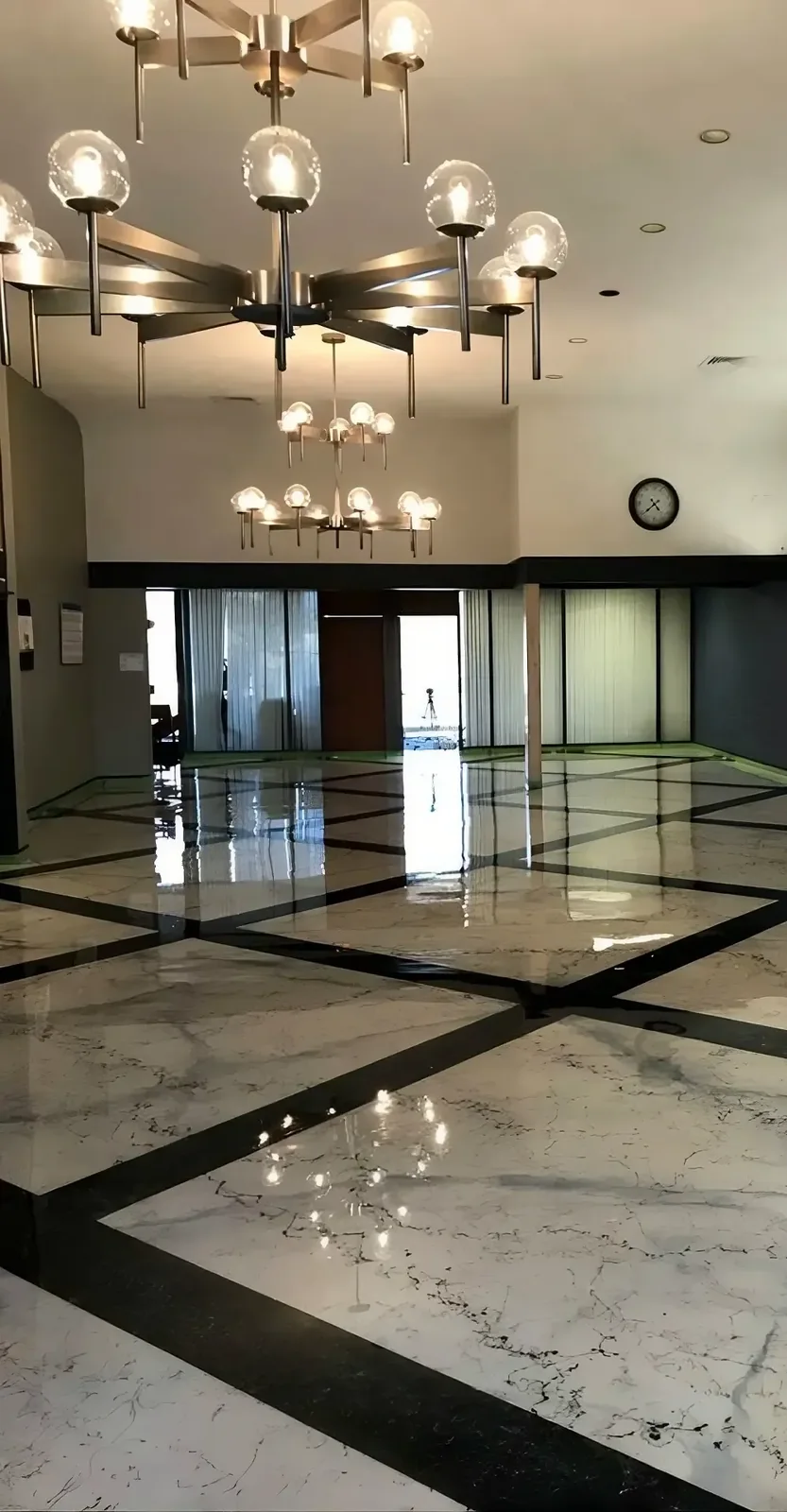 Italian Marble lobby floor in a cream and black diamond pattern reflecting the chandeliers overhead